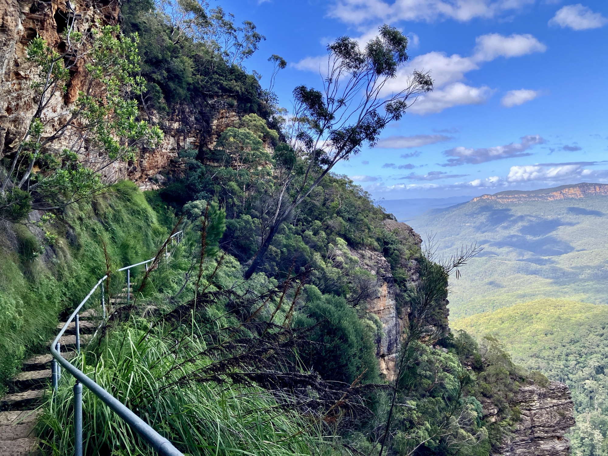 A stairway path along a clifftop looking over a vast valley